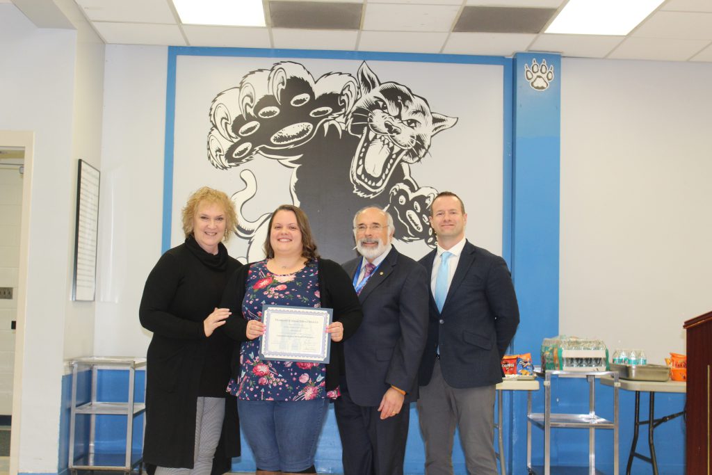 Samantha Acito stands with colleagues and holds her certificate 