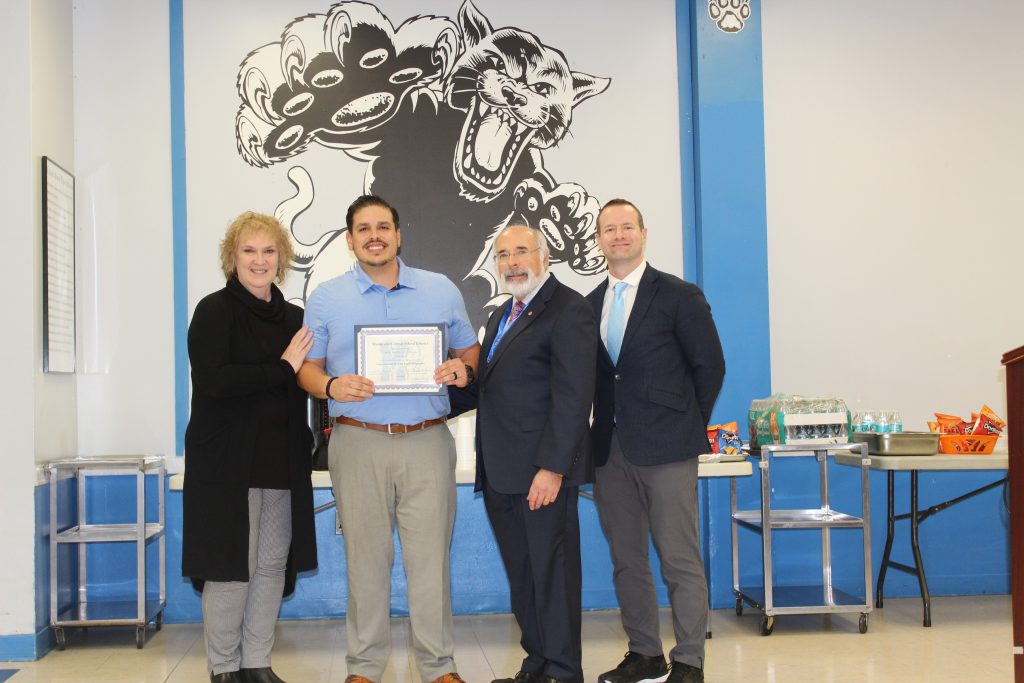 Michael Rojas stands with colleagues and holds certificate