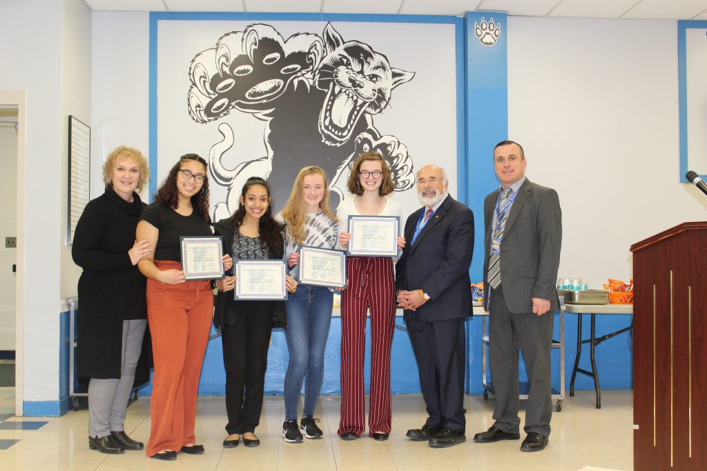 The girls cross country team is standing and holding their certificates 