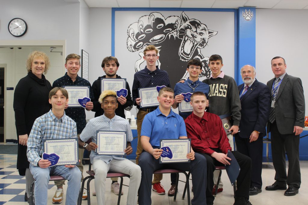 the boys cross country team is seated with their certificates 