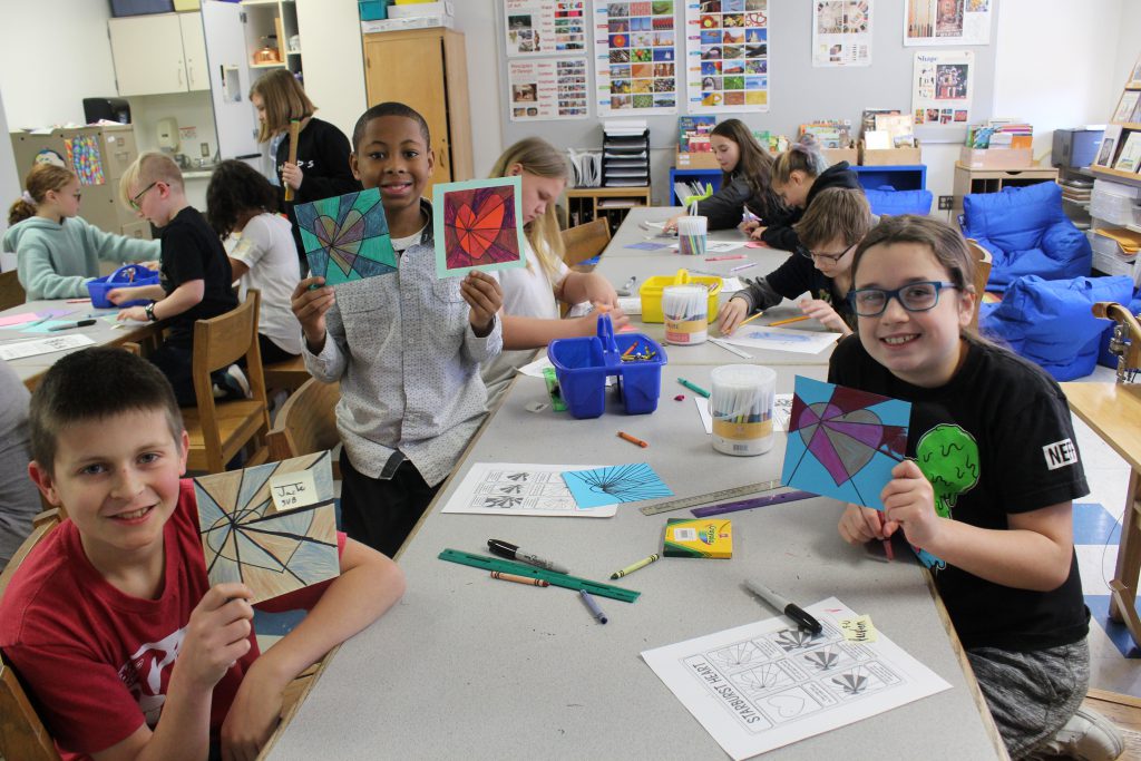 students hold up the Valentines they created 