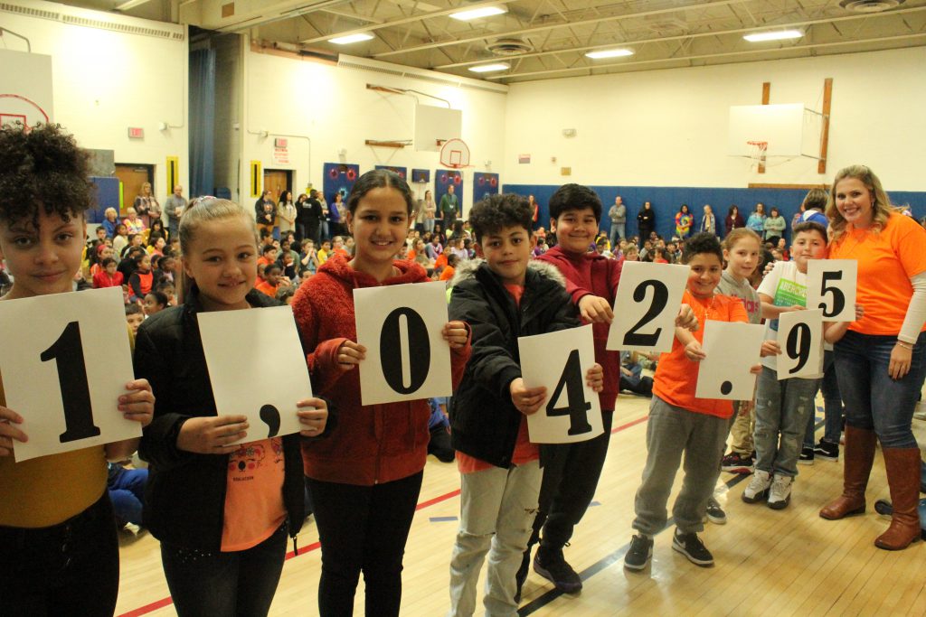 Eight students are holding up pieces of paper that when put together read #1,042.95