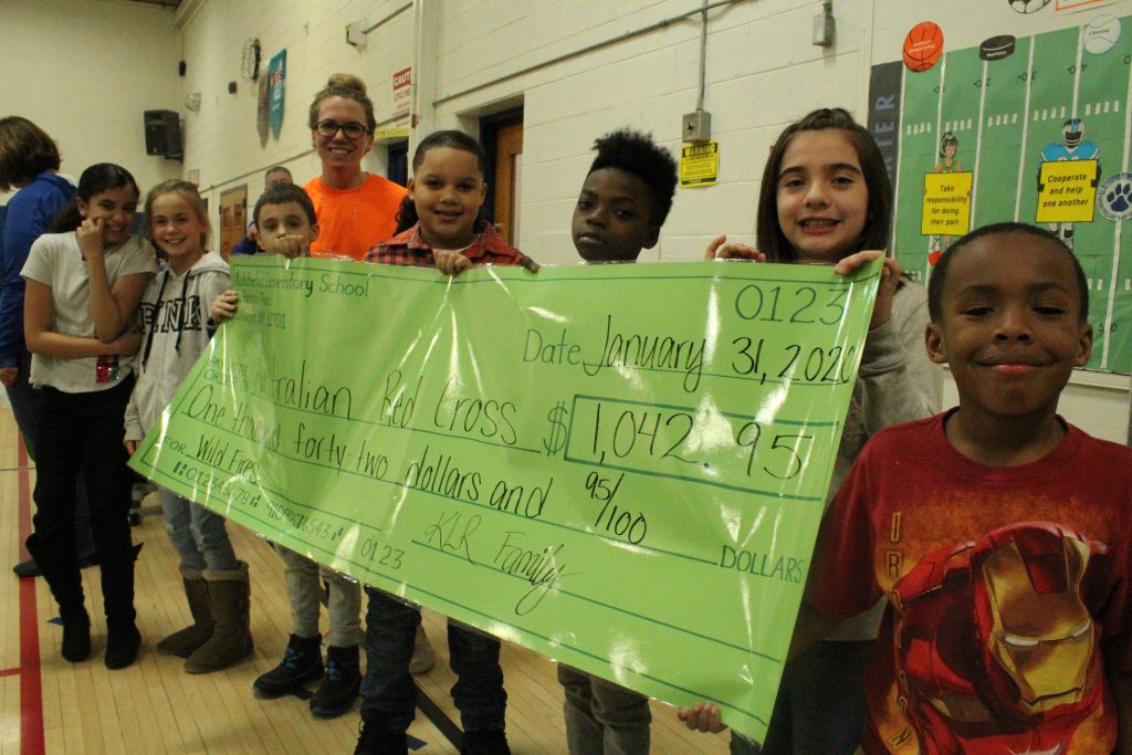 A group of students is holding up a large promotional check prop 