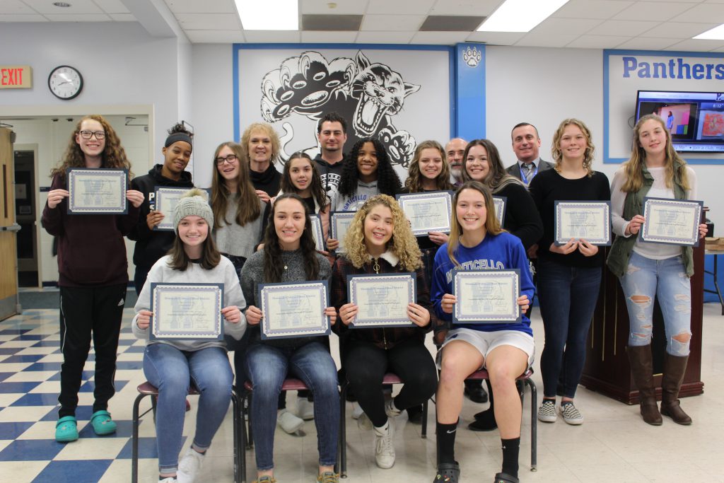 the girls soccer team is seated and holding their certificates