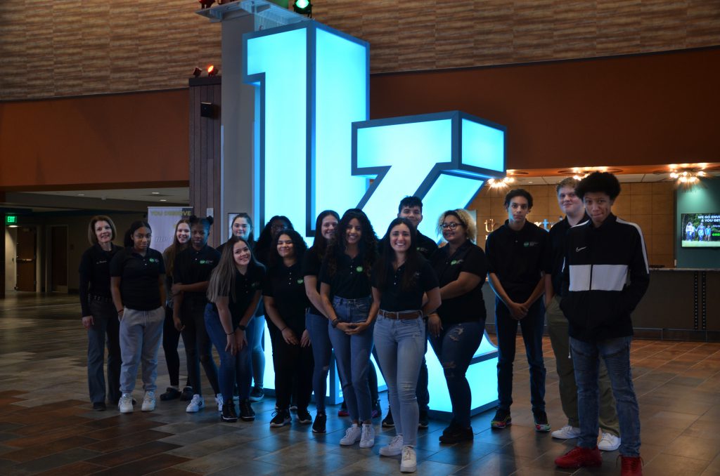 a group of students standing in front of a large "K"