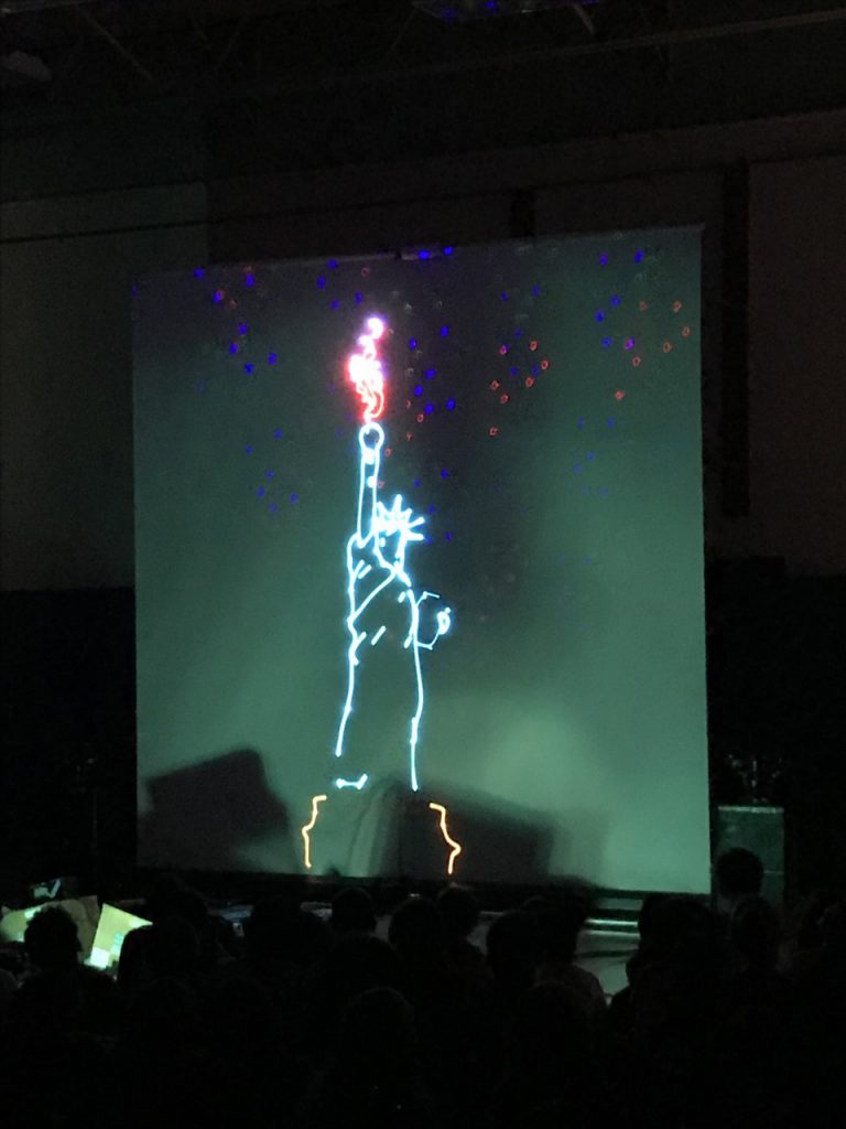 A dark room, green background with the statue of liberty in laser light