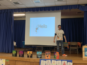 daniel miller is standing on a stage in the middle of presenting to students 