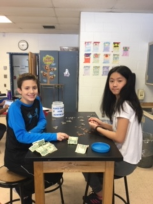 two students are sitting at a table and smiling into the camera