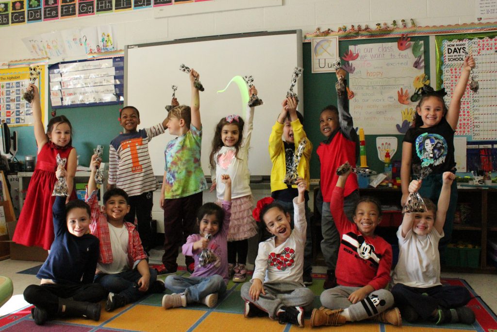 ms moore's class is holding up all of the gift bags 