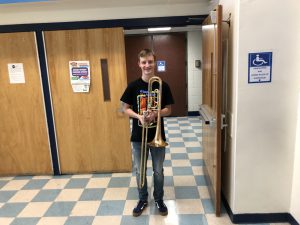 A young man holds a trombone