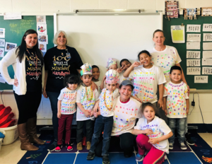 Mrs. Franzone and her students are wearing 100th day t-shirts and smiling 