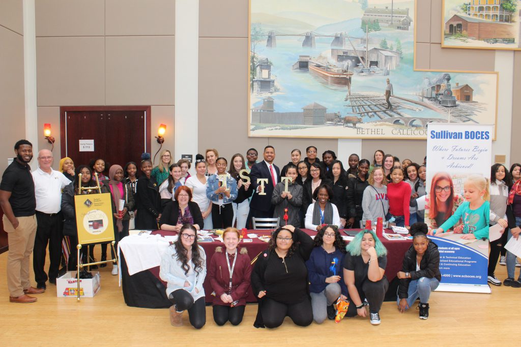 All of the participants are gathered in a hallway and smiling for the camera