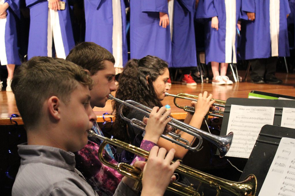 three students are playing the trumpet 