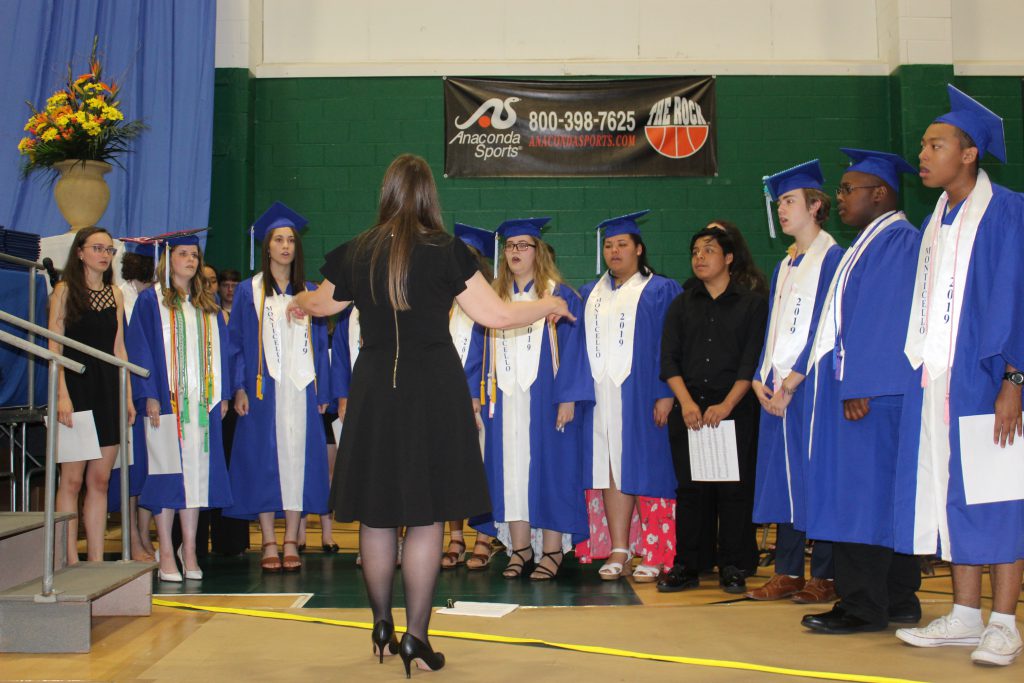 a group of students in graduation robes singing 