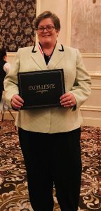 Rose Joyce Turner is standing in a room holding a certificate