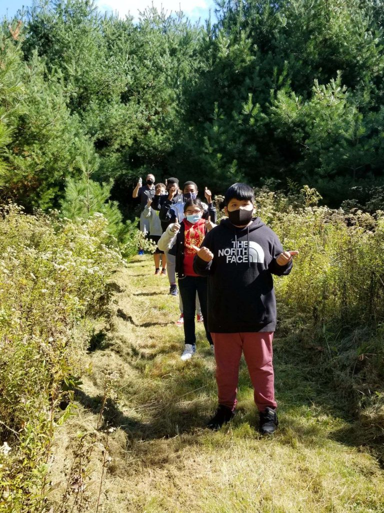 a group of students is walking through a path in the woods 
