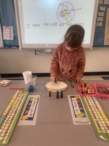 A student in Ms. Humberts class is standing at a desk and looking down at a plate 