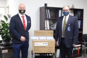 Todd Grodin and Matt Evans are standing with a box of masks in between them
