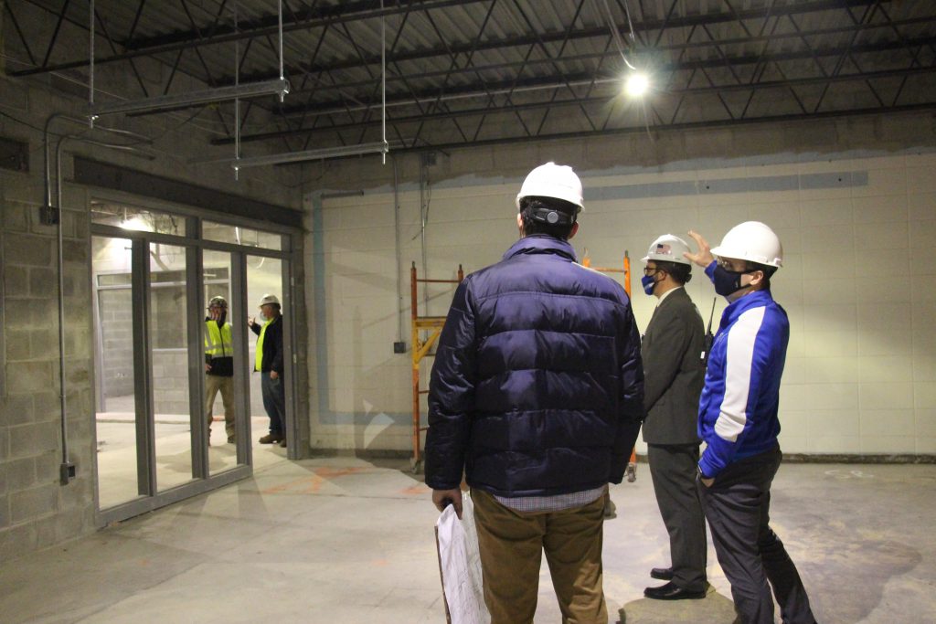 A group of people in hard hats look at the construction being done in a building.