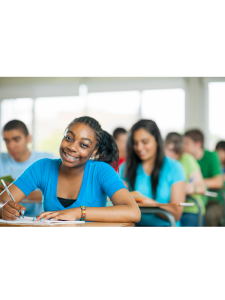 a student is sitting at a desk with a pencil in her hand and smiling at the camera