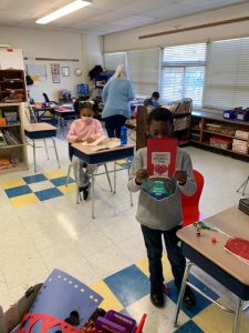 two students are holding up valentines cards that they drew