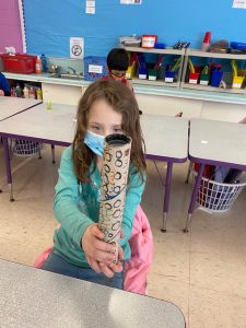 a young girl is stiing at a desk with a rain stick