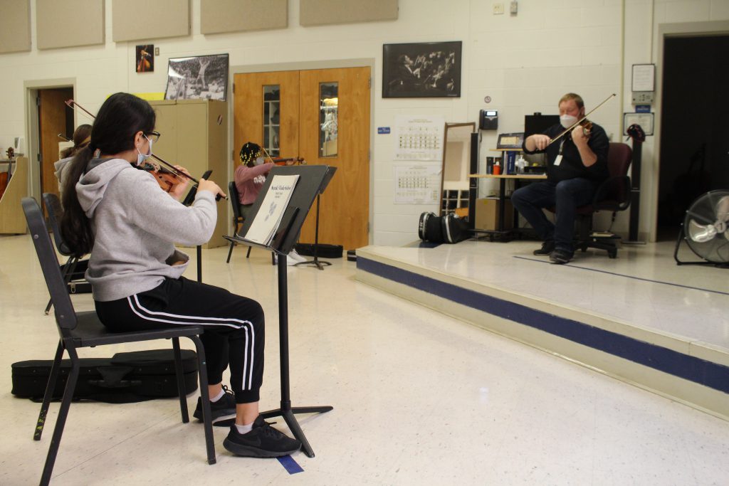 two students are playing violins 