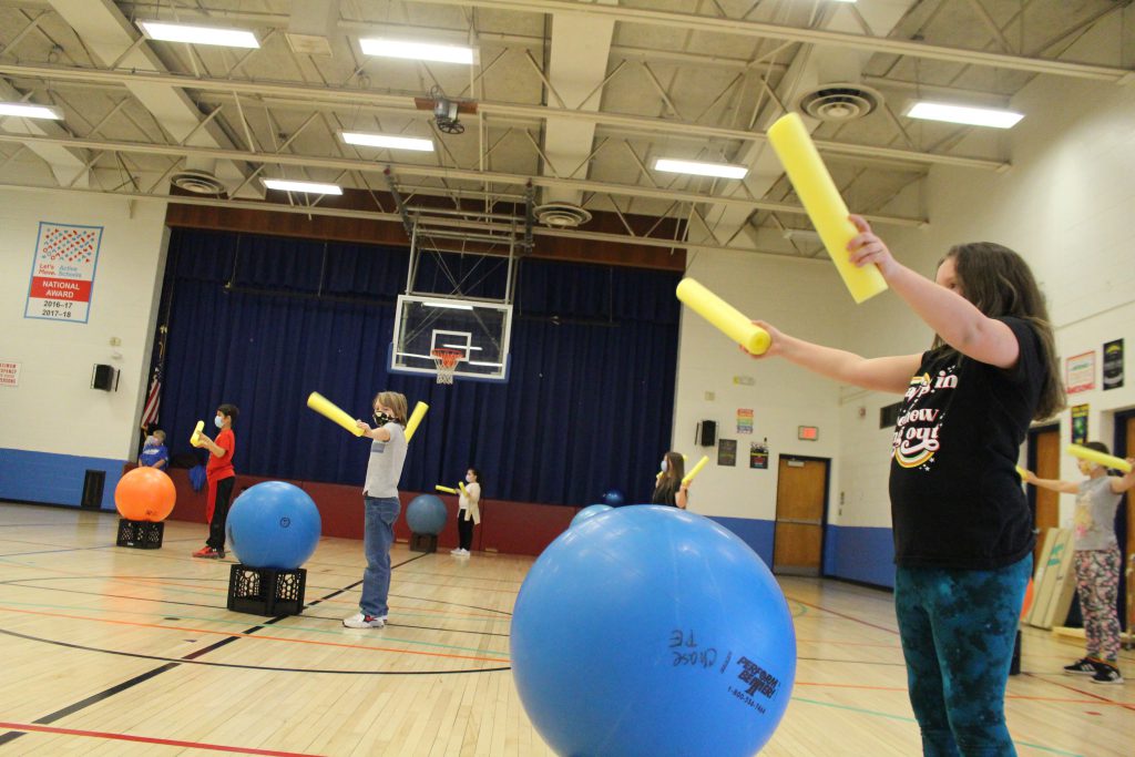 students are in a gym participating in cardio drumming 