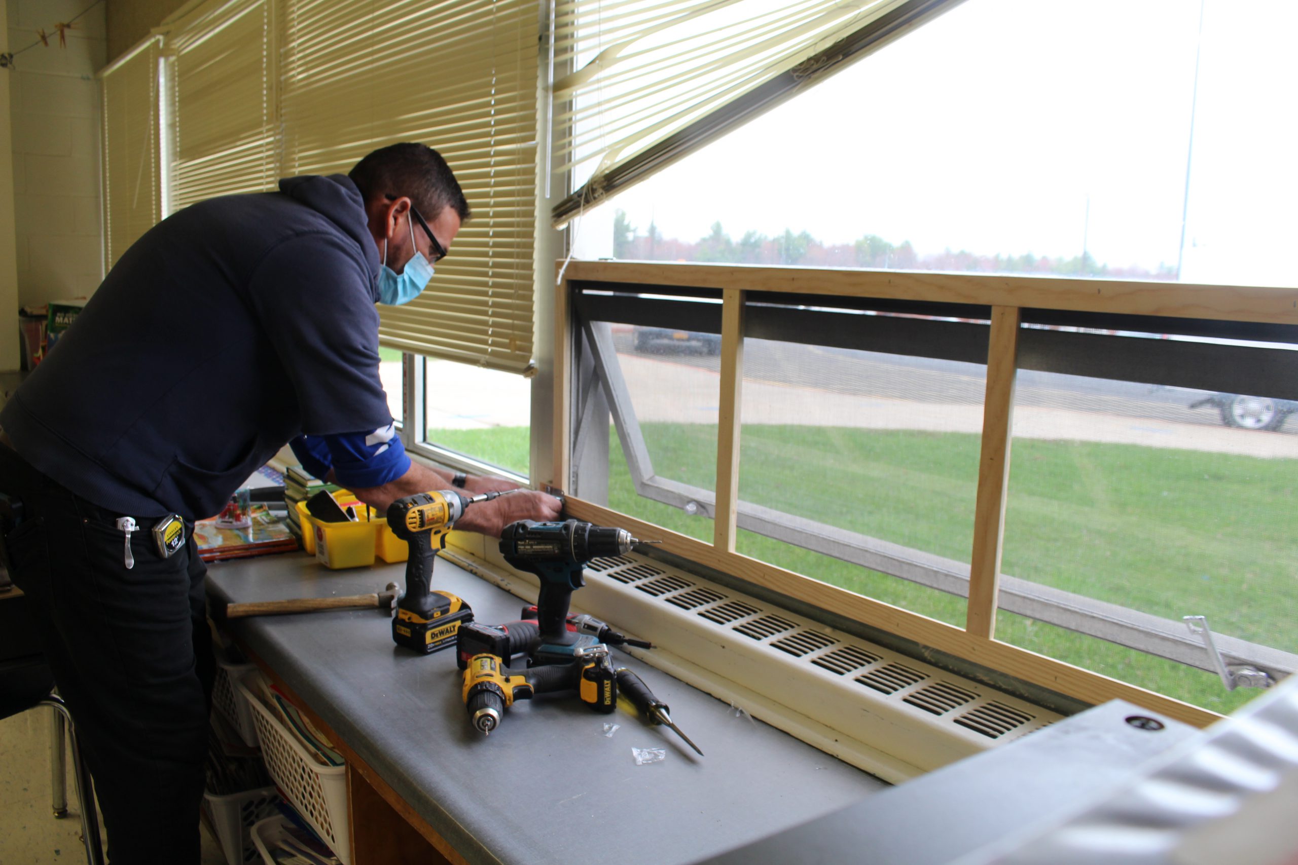 a man is screwing in a frame to a window