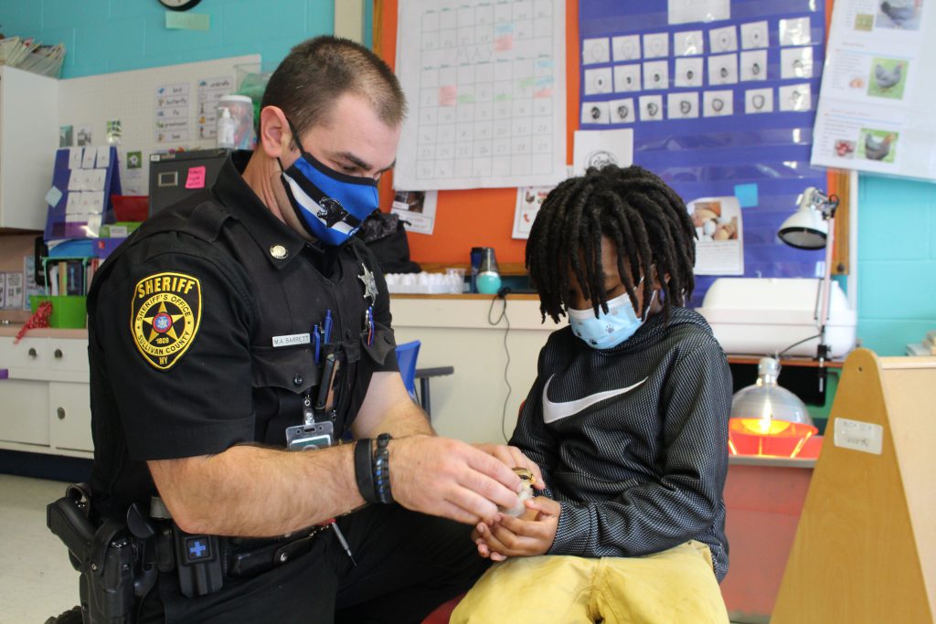 a police officer is handing a young boy a chick 