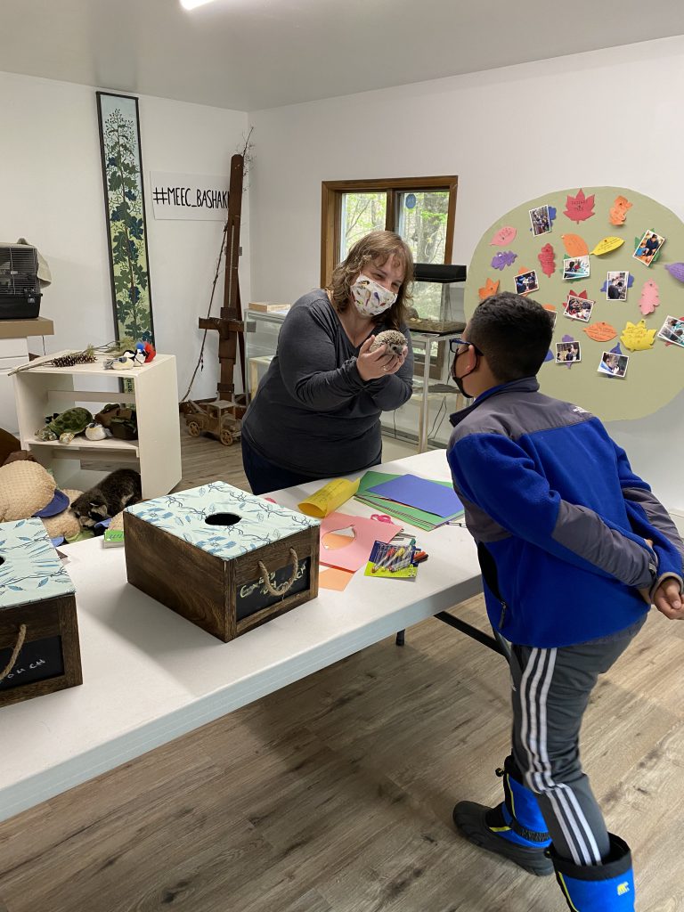 a Bashakill staff member is showing a hedgehog to a student