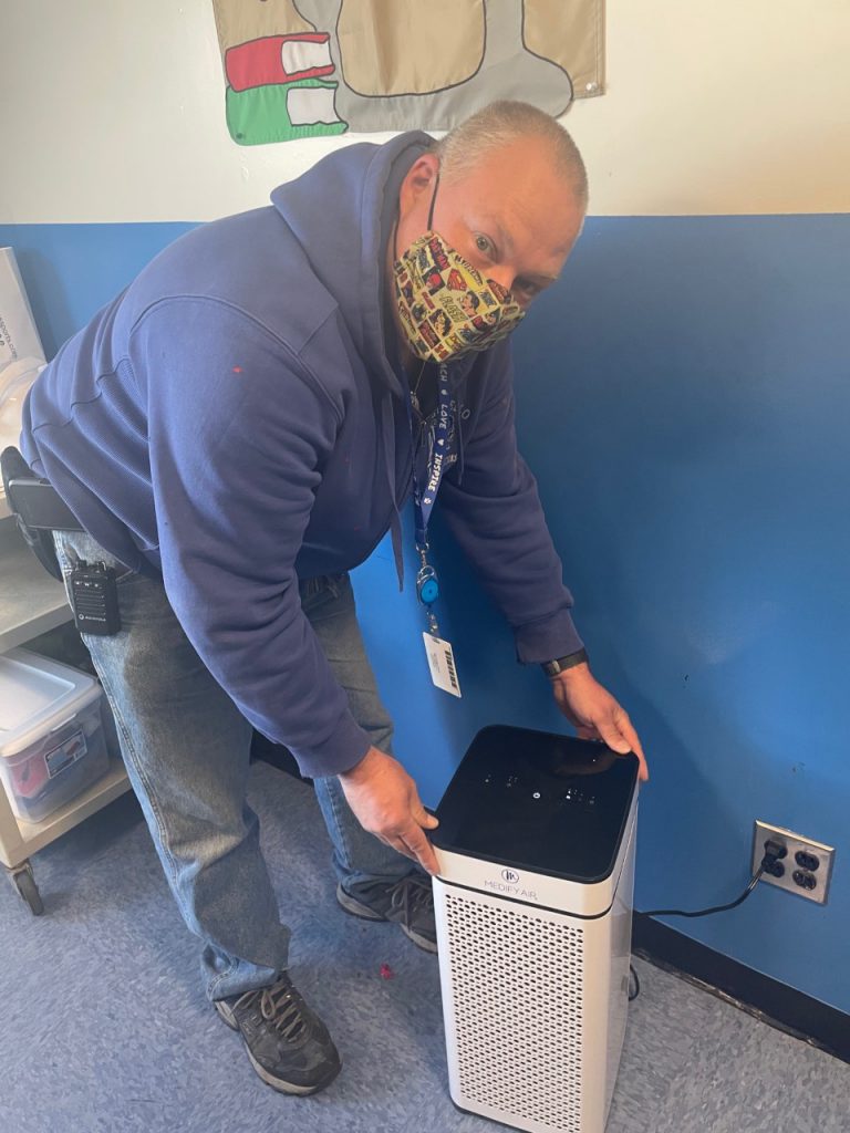 Charles Payne is hovering over an air filter, and is about to plug it into the wall 