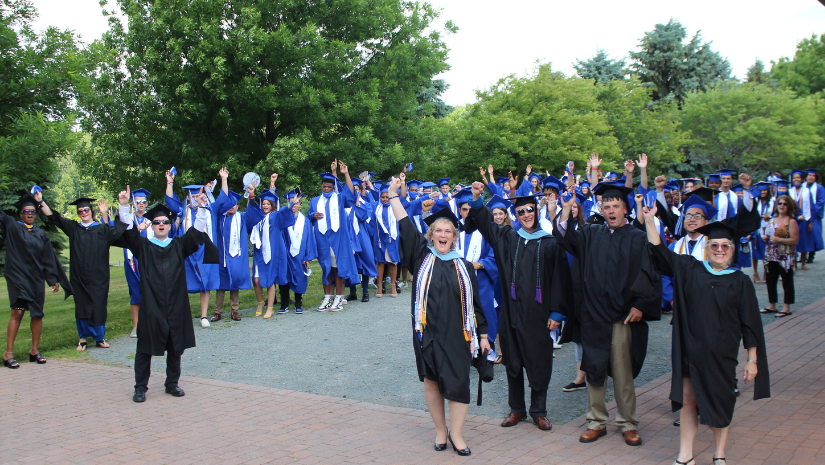 a large group of students in graduation gowns are standing in a group and thrusting their handsin the air in excitment