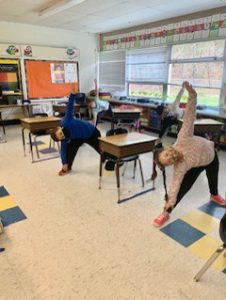 Elementary school kids doing yoga in a classroom.