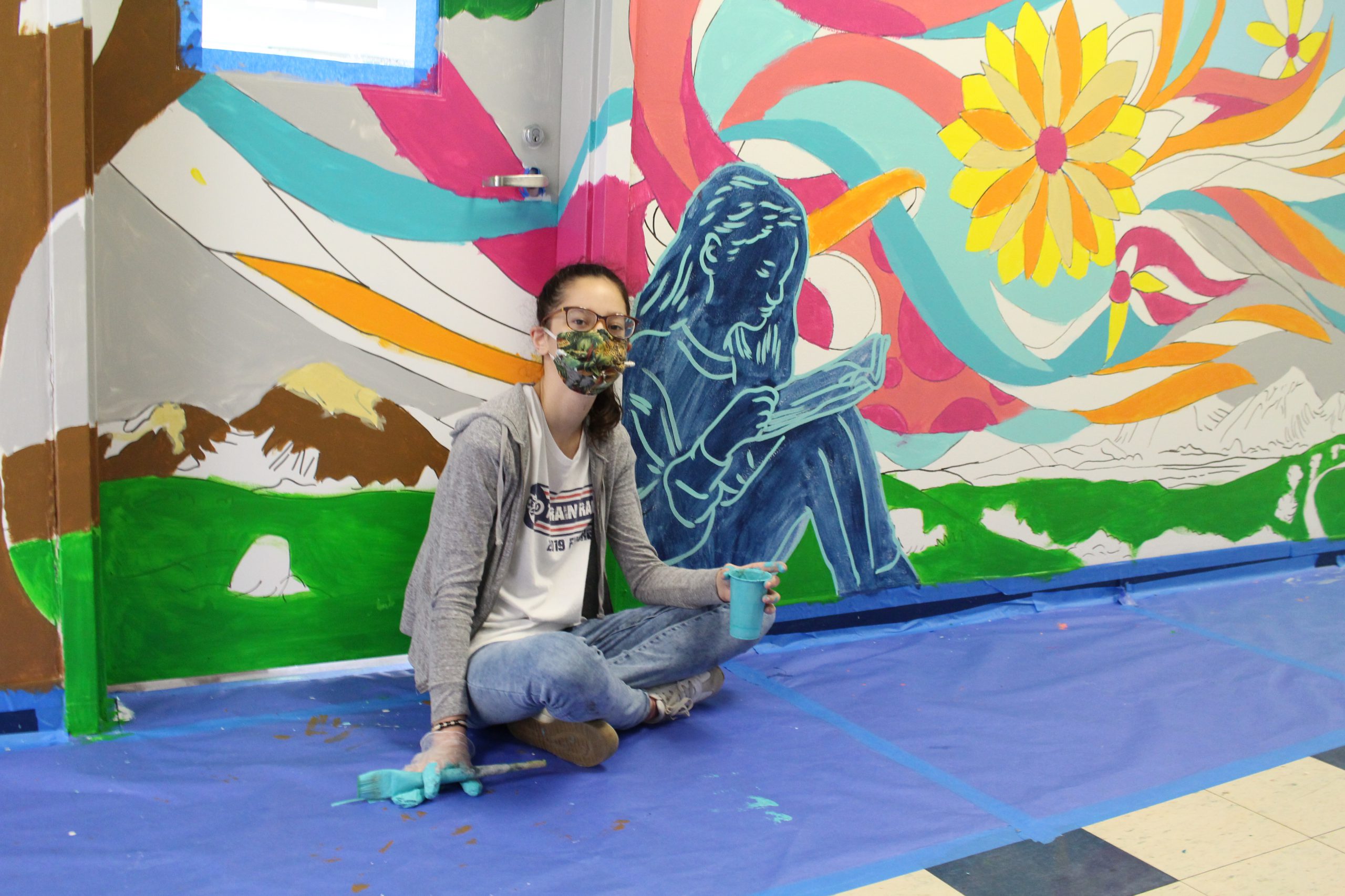 a student is sitting next to a drawing of herself