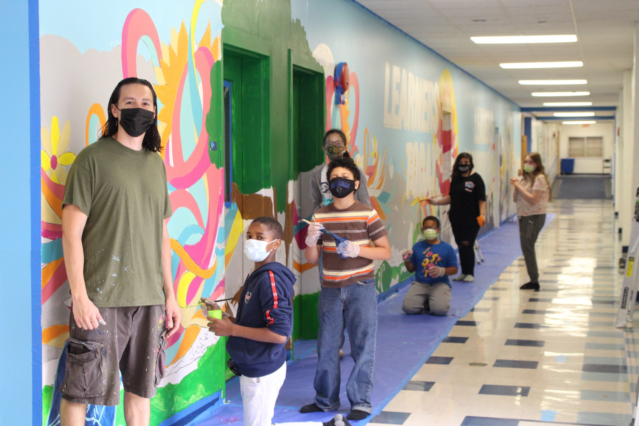 joe pimentel and student artists are standing next to the mural they created 