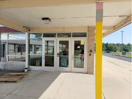 A covered entrance to a building with four glass doors.