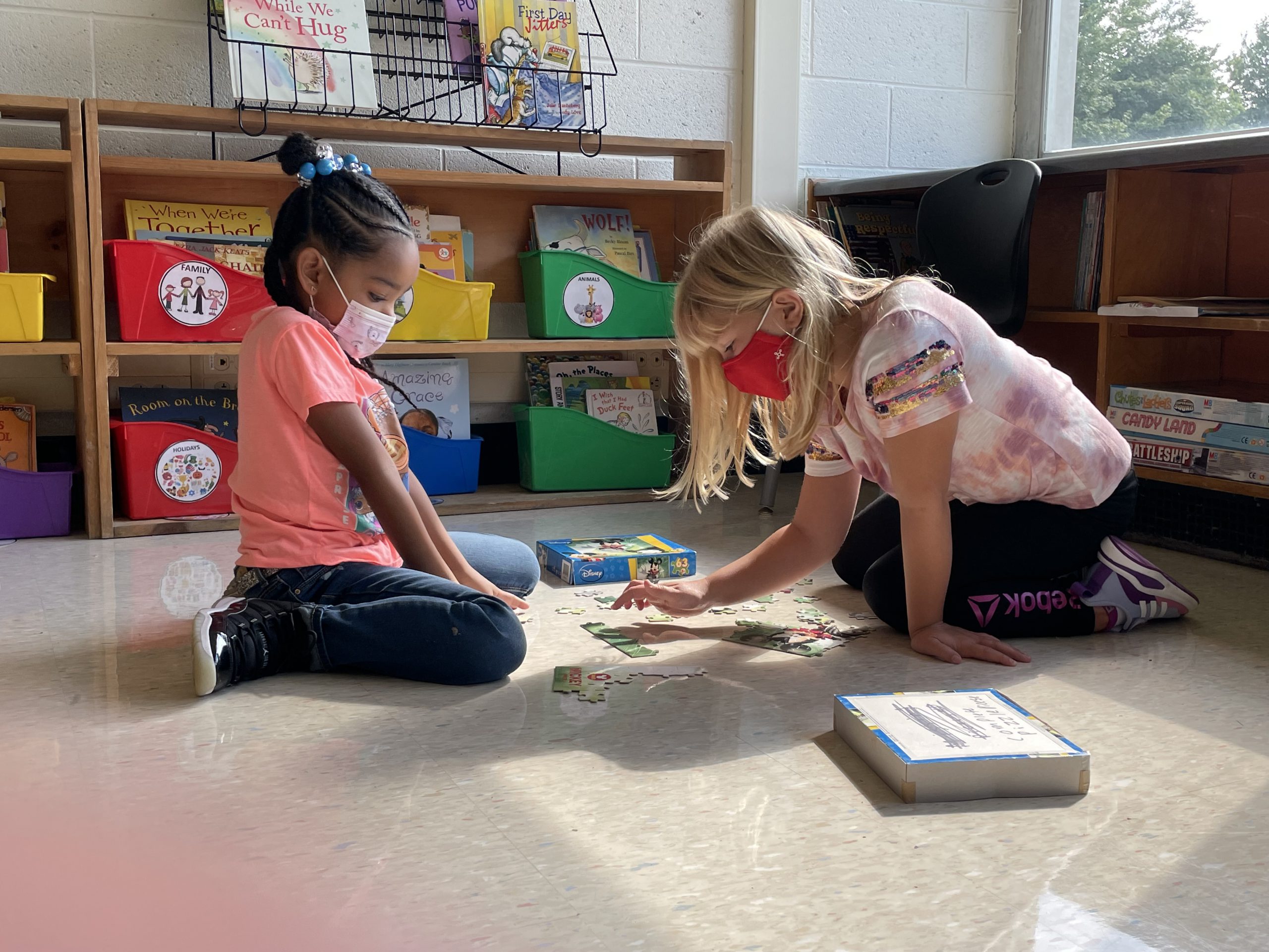 two students are seated on the floor working on a puzzle 