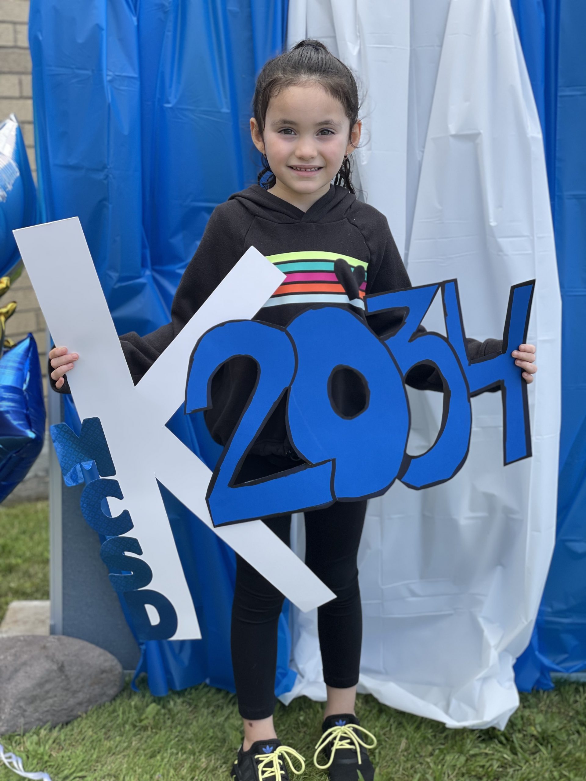 a young girl is holding up a sign that says class of 2034 