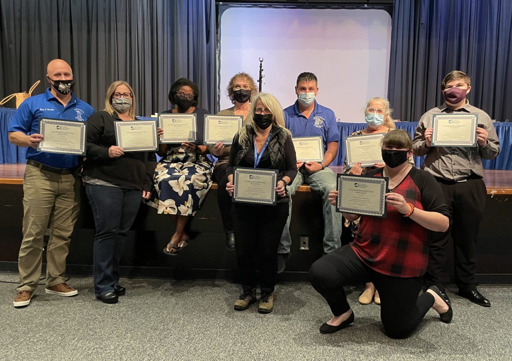 members of the MCSD Board of Education pose with certificates on the stage