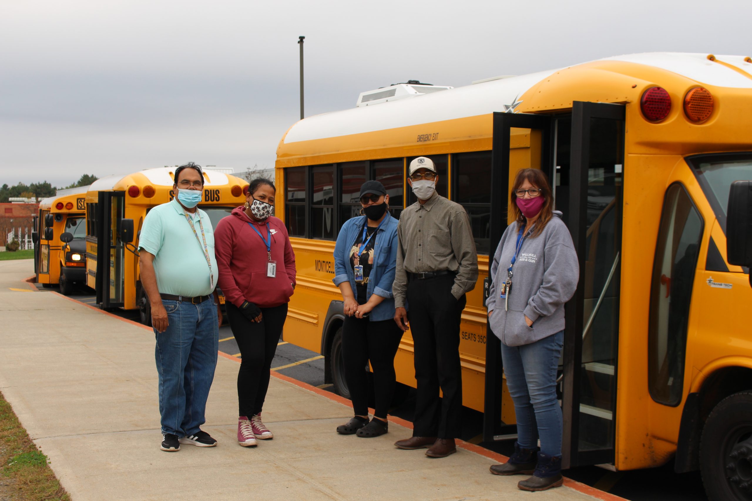 a group of bus drivers standing in front of a short bus