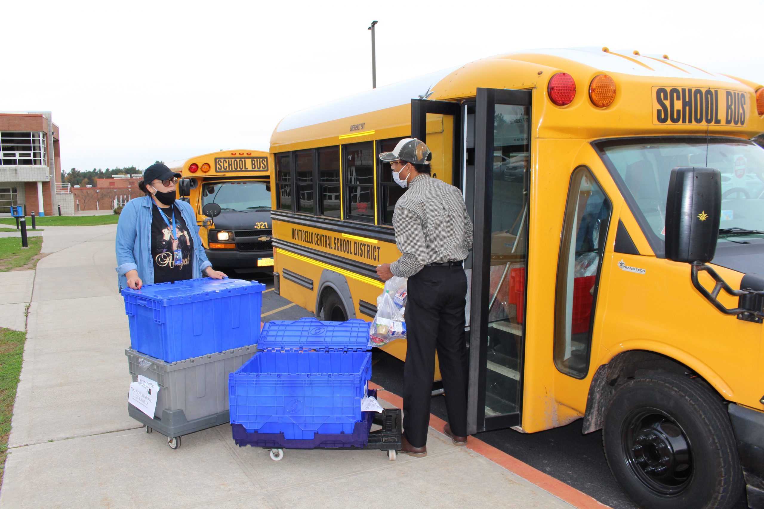 two drivers are lifting up crates of food to stock a bus