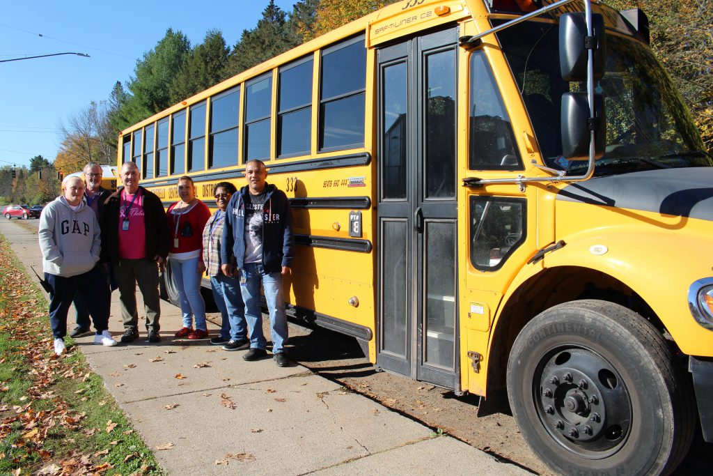 a group of bus drivers is standing in front of a school bus