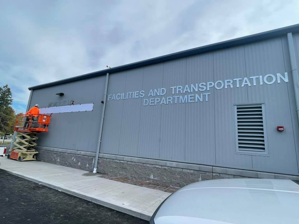 the facade of the new transportation center. Two workers are hanging a sign