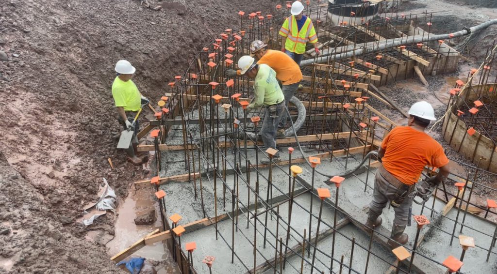 construction workers are engaged in work outdoors in the high school's courtyard. It is very muddy.