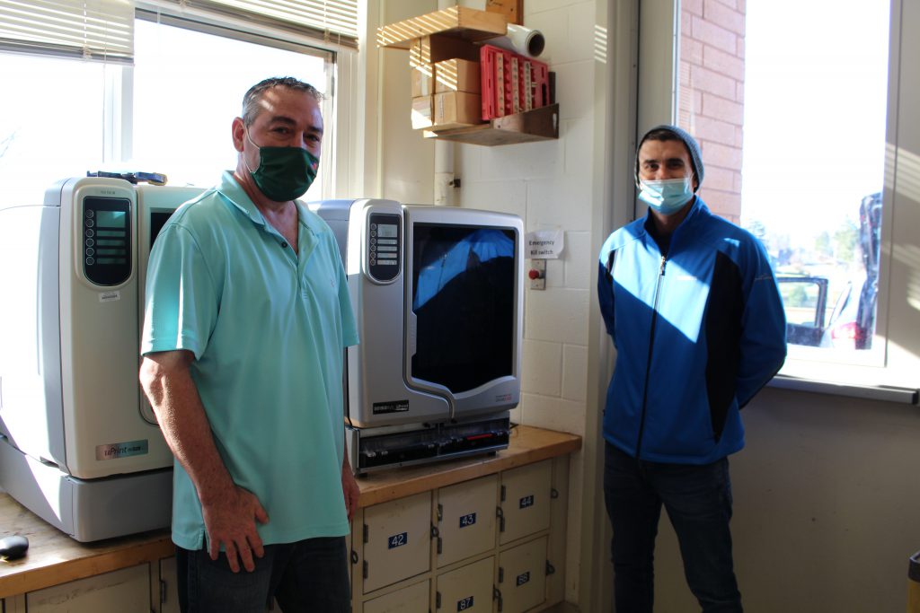 Mr. Oefelein and Mr. Music are standing with the new printer between them 