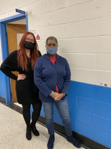 two school counselors are posing in a hallway