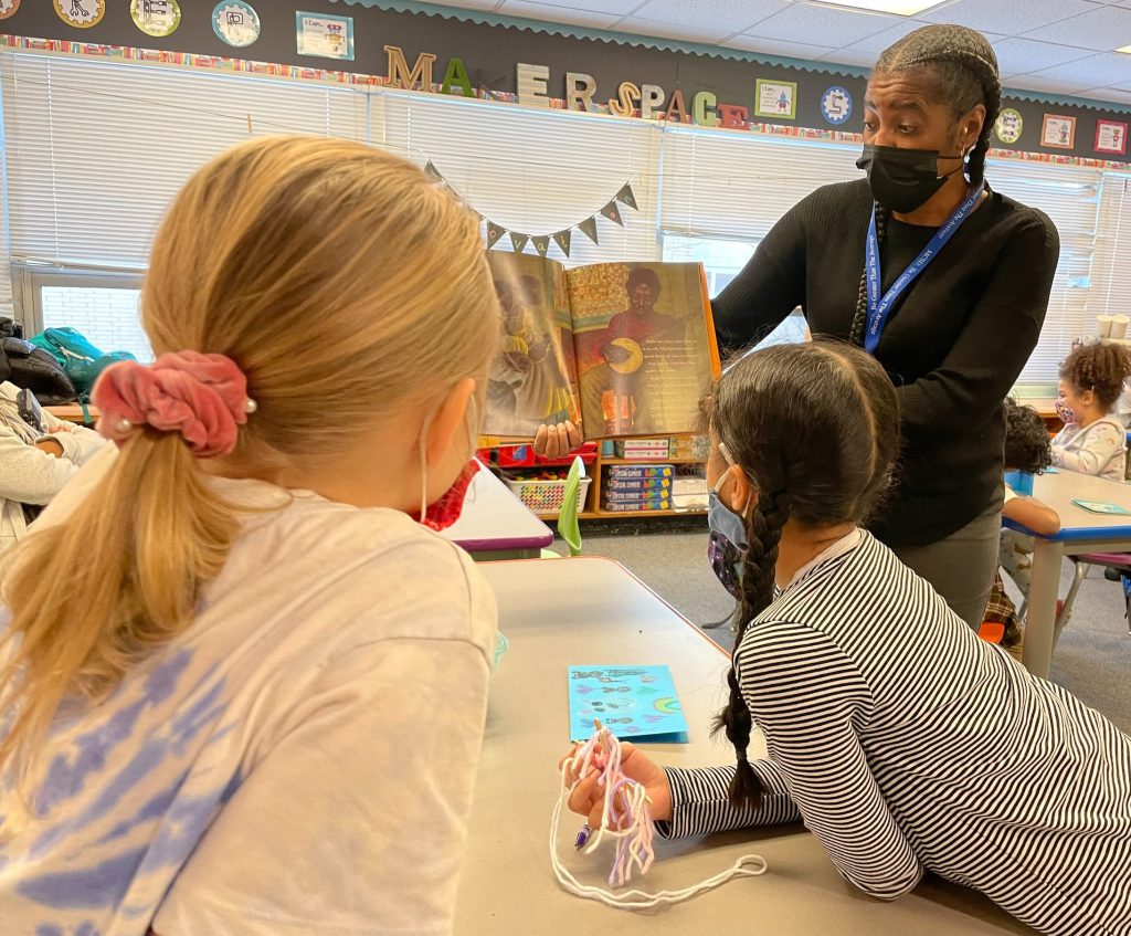 a teacher is standing over two students and showing them pages in the book