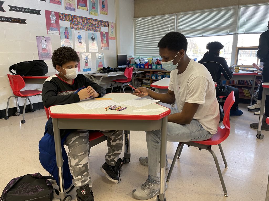 two male students are seated at a desk