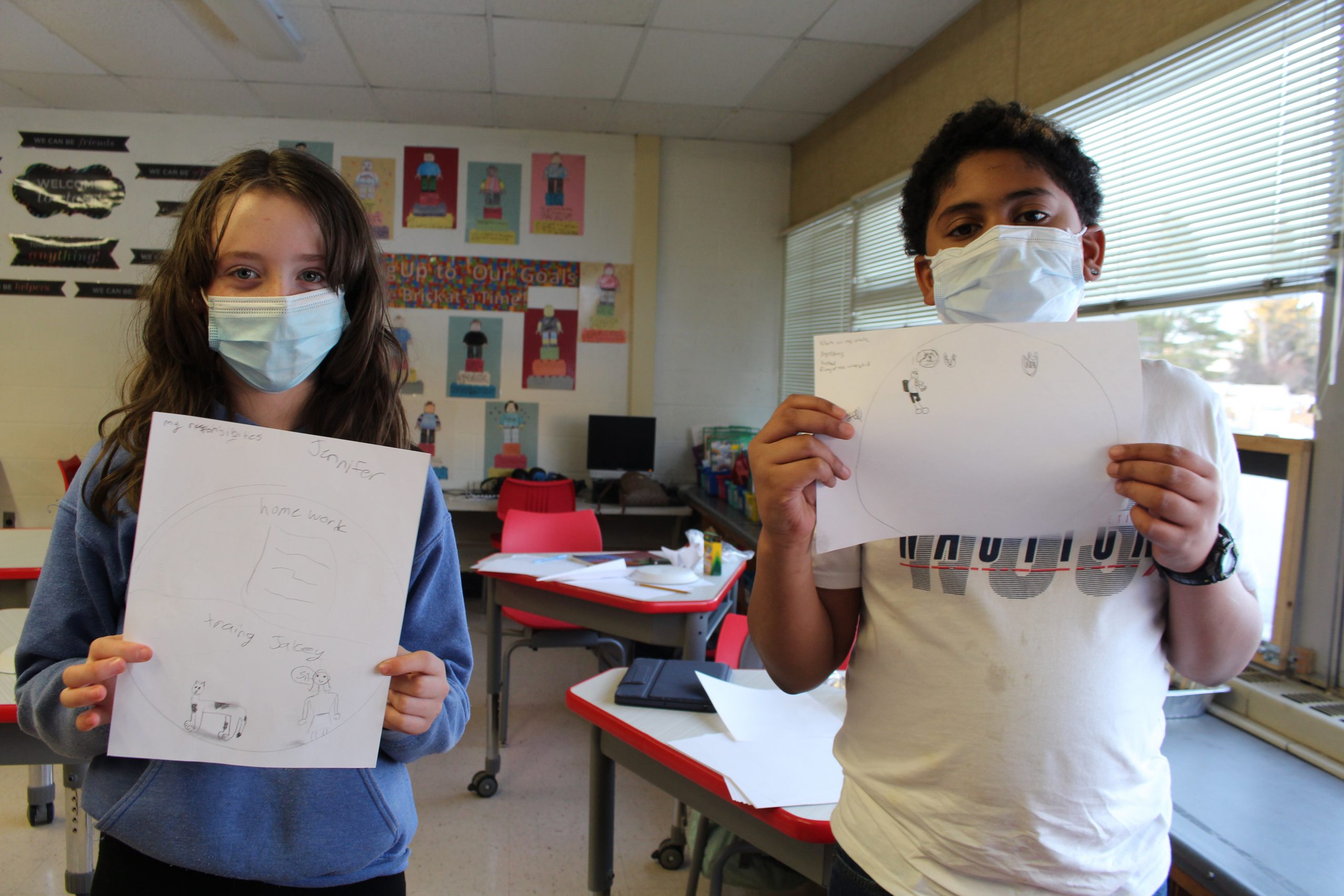 a female and male student are holding up pieces of paper that contain their work 